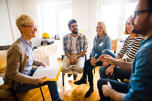 Group of people sitting in a circle on group therapy. Looking at their therapist and listening ti her story. Children’s Act 2004